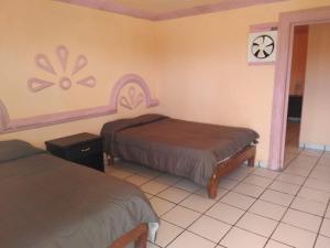 a room with two beds and a clock on the wall at Hotel Plaza Peñasco in Puerto Peñasco
