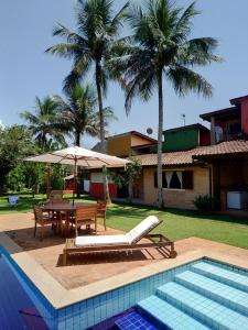 a pool with a table and chairs and a table and umbrella at Suíte Água Branca Residencial Exclusive in Ilhabela