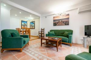 塔維拉的住宿－Casa Marés，客厅配有两张绿色沙发和一台电视机