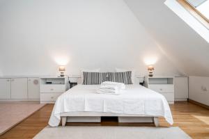 a white bedroom with a white bed and two lights at Casa Marés in Tavira