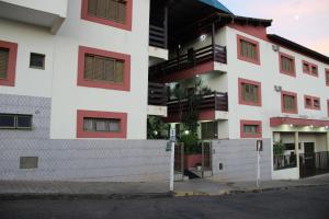 un edificio blanco con ventanas rojas y una calle en Hotel São Lucas, en Alfenas