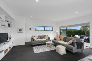 ein Wohnzimmer mit 2 Sofas und einem TV in der Unterkunft Cedar House - Martinborough Holiday Home in Martinborough 