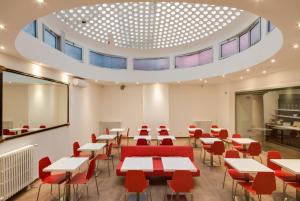 une salle de classe avec des tables et des chaises et un grand plafond dans l'établissement Genius Hotel Downtown, à Milan