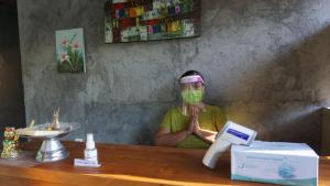 un hombre con una máscara en la cara sentado en un mostrador en Bougainvillea Bungalow, en Nusa Penida