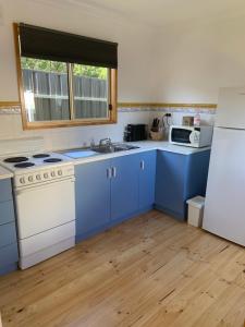 eine Küche mit blauen Schränken und einem weißen Kühlschrank in der Unterkunft Moana Beach Sunset Holiday Accommodation A in Moana