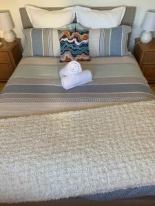 ein Bett mit zwei Handtüchern darüber in der Unterkunft Moana Beach Sunset Holiday Accommodation A in Moana