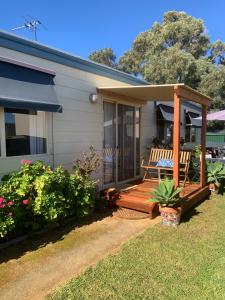 a house with a wooden porch with a bench on it at Moana Beach Sunset Holiday Accommodation A in Moana