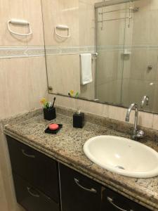 a bathroom counter with a sink and a mirror at Apartamento Elizabetta 3, pé na areia in Arraial do Cabo +17 photos