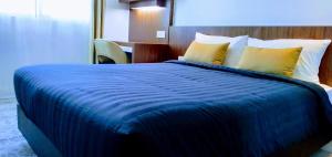 um quarto com uma grande cama azul com almofadas amarelas em UTM Hotel & Residence em Kuala Lumpur