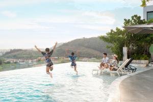 two children jumping into the water in a swimming pool at Holiday Inn & Suites Siracha Laemchabang, an IHG Hotel in Si Racha