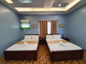 two beds in a room with blue walls at Ralphseej Pension House in Moalboal
