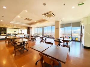 Un restaurante con mesas, sillas y ventanas. en Hotel 88 Embong Malang Tunjungan Surabaya by WH - Breakfast with The Best View on The Highest Floor and Strategic Location in The City Center, en Surabaya
