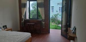 a bedroom with a bed and a window and a table at Linkin House in Phu Quoc