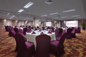 a conference room with tables and purple chairs at favehotel Premier Cihampelas in Bandung