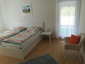 um quarto com uma cama, uma cadeira e uma janela em Am Mühlbach em Sinsheim