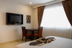 a room with a bed and a table and a television at Club Mahindra Mac Boutique Hotel in Bangkok