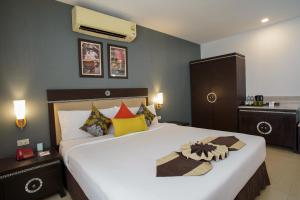Club Mahindra Mac Boutique Hotel في بانكوك: غرفة نوم مع سرير أبيض كبير مع وسائد ملونة