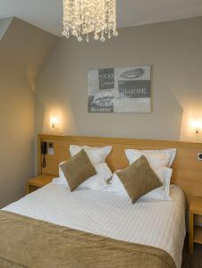 1 dormitorio con 1 cama grande con sábanas y almohadas blancas en Hôtel Le Vouglans - Restaurant La Valouse, en Orgelet
