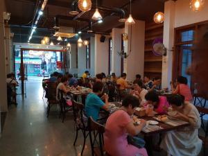 un grupo de personas sentadas en mesas en un restaurante en Vina Carnosa Hotel Hue, en Hue