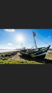 un bateau assis sur la rive d'une plage dans l'établissement Escale beauté le Crotoy, au Crotoy