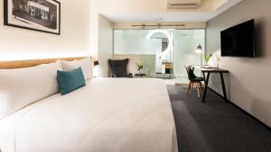 a bedroom with a large white bed and a desk at Hotel Room @ 89 Courtenay Place in Wellington