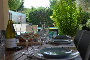 バニョール・シュル・セーズにあるLes Hauts de Chaudeyracのグラスと皿、ワイン1本が備わるテーブル