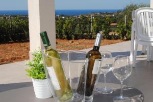 two bottles of wine sitting on a table with wine glasses at Villa Edori - Giardino degli Allori in Castellammare del Golfo