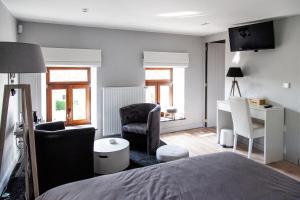 a bedroom with a bed and a desk and a chair at La maison en pierre in Jodoigne