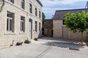 JodoigneにあるLa maison en pierreの石造りの建物2棟と木が並ぶ中庭