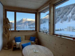 Cette chambre comprend une table, des chaises et des fenêtres. dans l'établissement Vinadi, à Davos