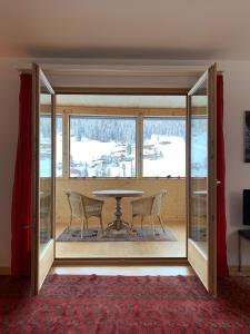 uma sala de jantar com mesa, cadeiras e janelas em Vinadi em Davos