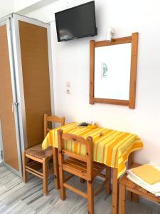 a room with a table and chairs and a television at Prombona Petrino Spiti Studios in Piso Livadi