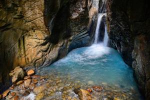 einen Wasserfall in einer Höhle mit einem Pool aus Wasser in der Unterkunft Alpenrose in Innertkirchen