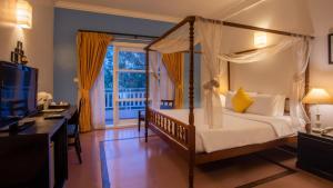 a bedroom with a canopy bed and a desk and a television at Amber Angkor Villa Hotel & Spa in Siem Reap +75 photos