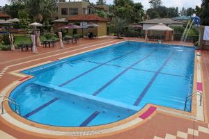 a large blue swimming pool with tables and umbrellas at Dereva Hotel Rwamagana in Rwamagana