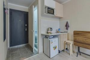 eine kleine Küche mit Kühlschrank und Mikrowelle in der Unterkunft YourHouse на Гагарина Утепова - экономичнее квартиры, уютнее гостиницы in Almaty + 34 Fotos