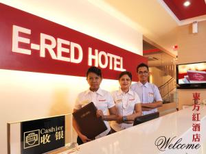 tres hombres parados frente a una señal roja de hotel en ERNES Hotel en Perai