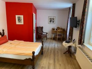 ein Schlafzimmer mit einer roten Wand, einem Bett und einem Tisch in der Unterkunft Altstadthotel Wilde Rose in Eppingen