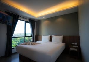 a bedroom with a large bed with a large window at The Zleep Chonburi in Chon Buri