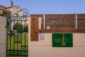 a green sign on the side of a house with a gate at Eleni's Family Villa in Laganas