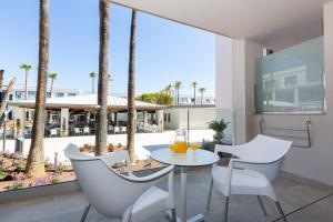 einen Balkon mit einem Tisch, Stühlen und Palmen in der Unterkunft Hipotels Barrosa Park in Chiclana de la Frontera