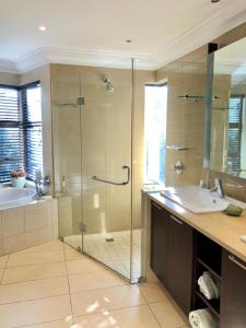 a bathroom with a glass shower and a sink at Villa with a view in Ballito