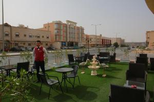 a man standing in a yard with chairs and tables at Rahty Home Hotel Apartments in Riyadh