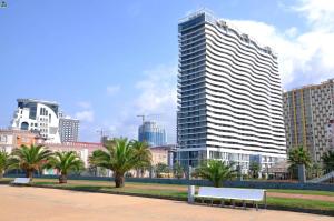a tall building with a bench in a city at Orbi Residence Sea View in Batumi