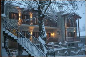 un gran edificio con escaleras cubiertas de nieve y un árbol en 4 Epohes, en Elati