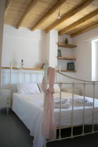 Un dormitorio con una cama blanca con un arco rosa. en Traditional suites in Chora Kythnos #3, en Kithnos
