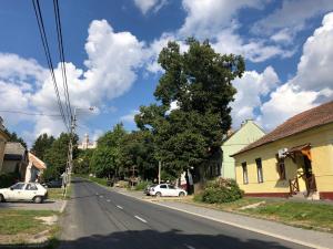 una calle vacía en un pequeño pueblo con coches aparcados en IL-LAK Apartment, en Pannonhalma