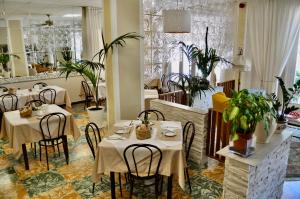 a restaurant with tables and chairs and plants at Hotel Corallo B&B in Cattolica