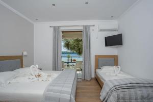 two beds in a room with a window and a tv at Mare Vita Apartments in Nydri