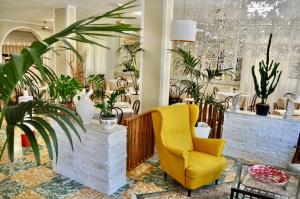 ein gelber Stuhl in einem Raum voller Pflanzen in der Unterkunft Hotel Corallo Garnì in Cattolica